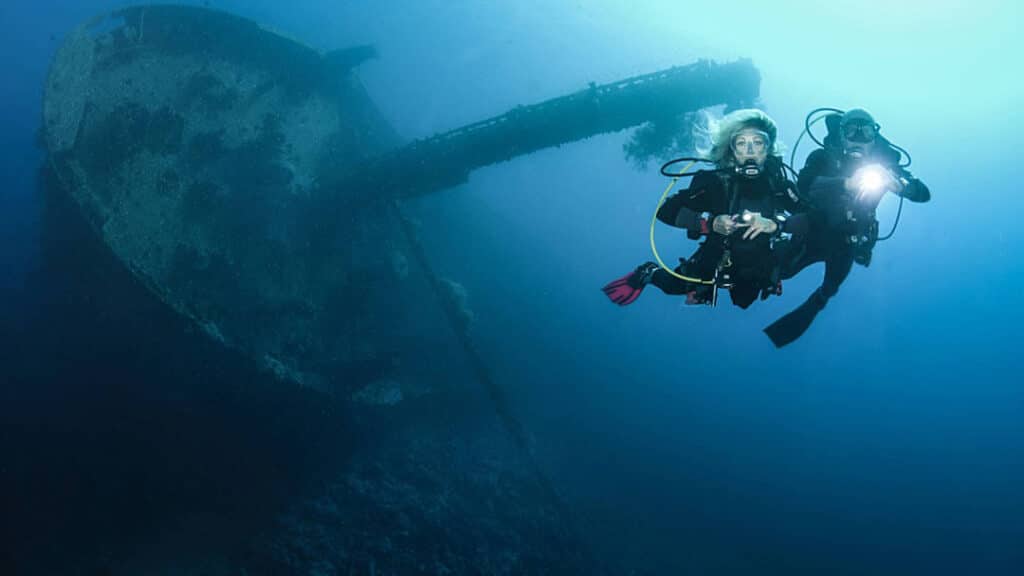 Man and woman diving next to shipwreck