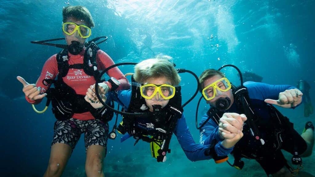 Three individuals in scuba gear swim gracefully underwater, discovering the beauty of the ocean's depths.