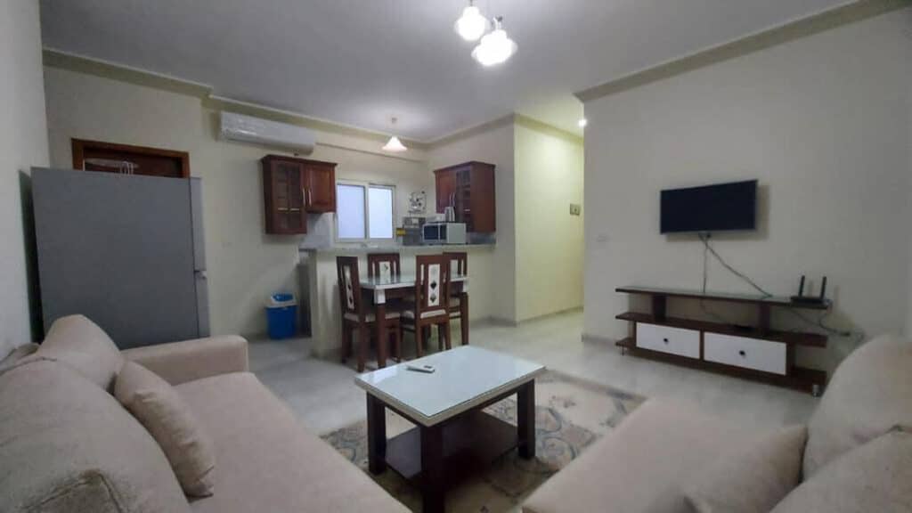 A cozy living room and kitchen area in a small apartment, featuring modern furnishings and warm lighting.