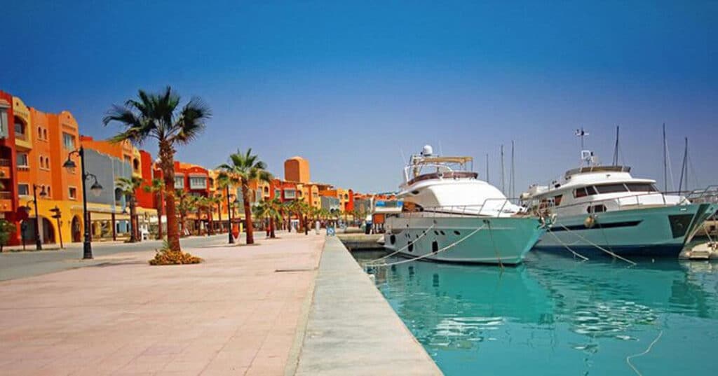 Boats are docked in the water beside a vibrant, colorful building, creating a picturesque waterfront scene.