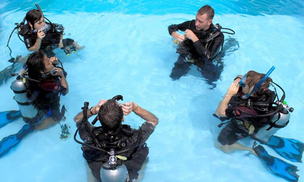 A group of diving trainees with their instructor in the swimming pool during training.