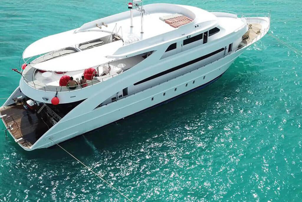 A white diving boat cruises through the Red Sea, showcasing a spacious deck and serene surroundings under a clear blue sky