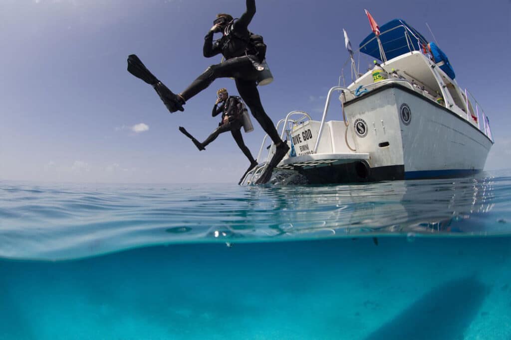 Two scuba divers leaping off a boat into the clear blue water, ready for an underwater adventure.