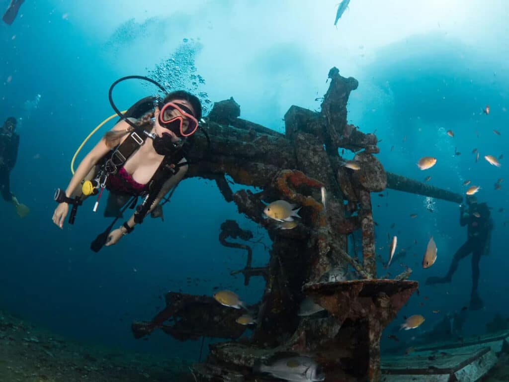 A group of divers near a shipwreck during a dive.