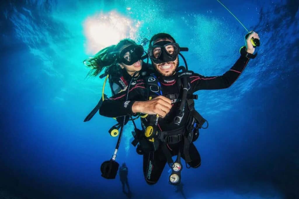 Two divers exploring the colorful underwater world during a dive trip in Hurghada, laughing underwater.