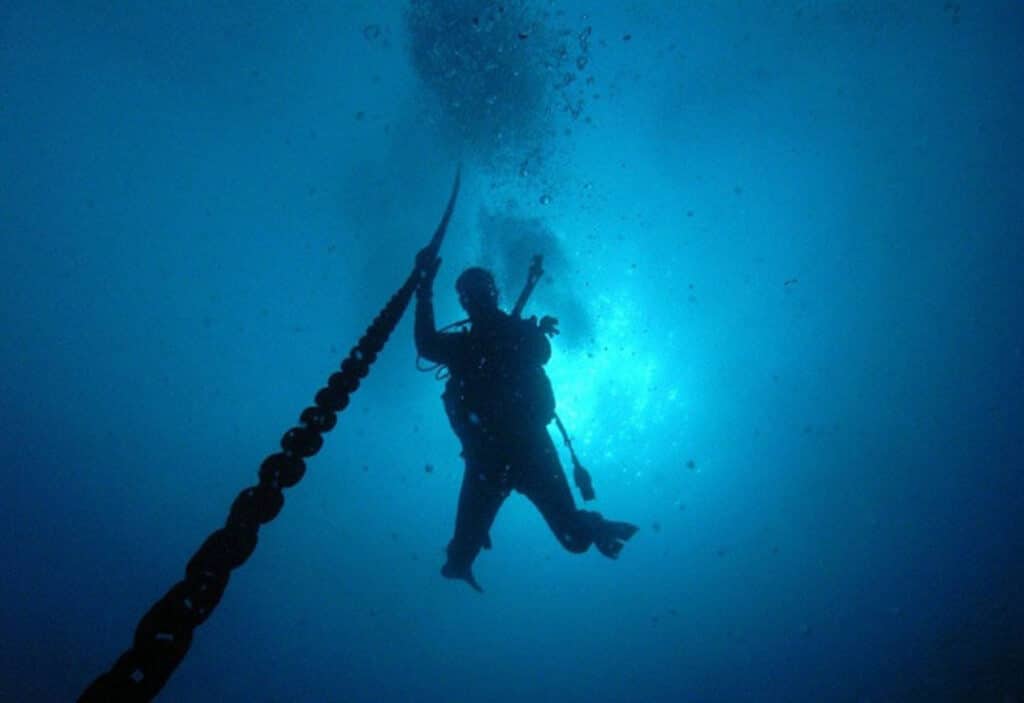 Young man diving into the depths near a rope