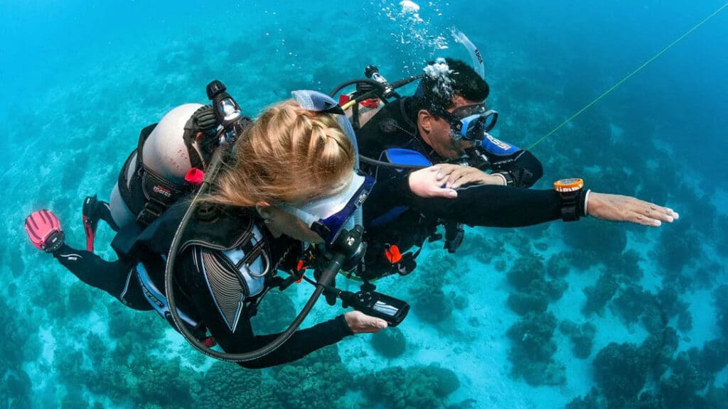 Man and woman finding directions underwater using maps and compass